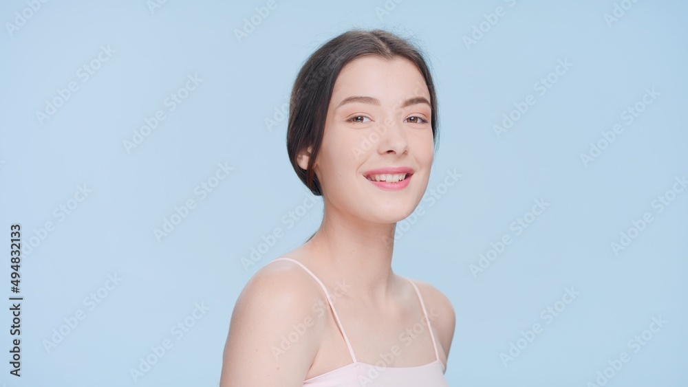 Close-up beauty portrait of young positive joyful brunette woman with a perfect skin turns and looks at camera and smiles | skincare products commercial concept. Close-up beauty portrait of young positive joyful brunette woman with a perfect skin turns and looks at camera and smiles | skincare products commercial concept.