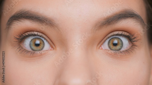 Extreme close-up of young woman with wide open eyes making surprised expression