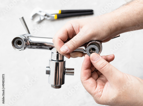 top view of plumber hands install paronite gasket in shower faucet and adjustable wrench on concrete board in background