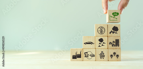 Low carbon emission and net zero concept. Climate changing problems solving goals. Stacking wooden cubes with decarbonization icon on pollution causes icons on grey background,copy space. LCA. photo