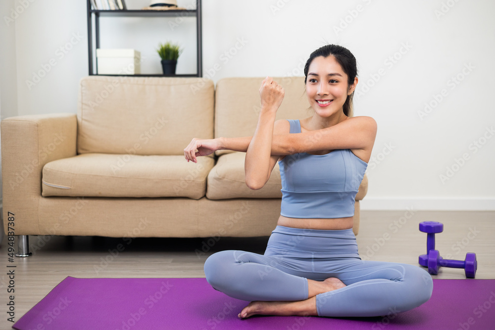 Attractive asian young fitness woman stretching arms warming up before workout at home. Beautiful smiling Female wearing sportswear exercise training yoga in living room. Attractive asian young fitness woman stretching arms warming up before workout at home. Beautiful smiling Female wearing sportswear exercise training yoga in living room.