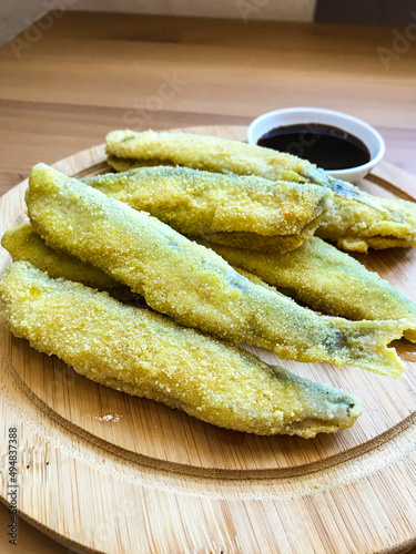 Pan fried fish on a plate. Capelin fried in oil with crispy breading.