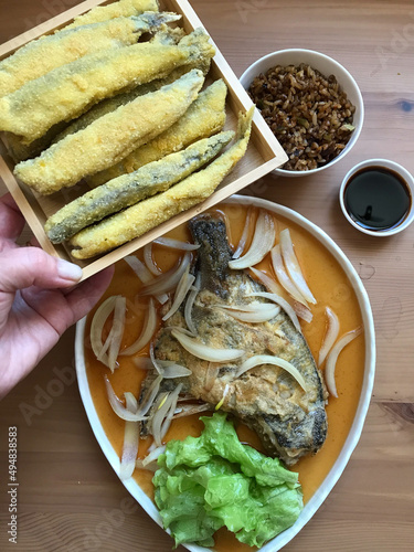 deep-fried flounder with onions and vegetables in Asian sauce on a plate.