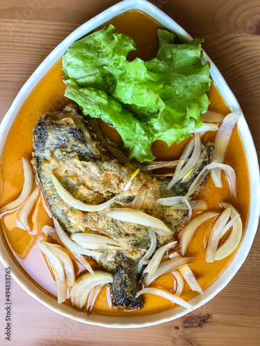 deep-fried flounder with onions and vegetables in Asian sauce on a plate.