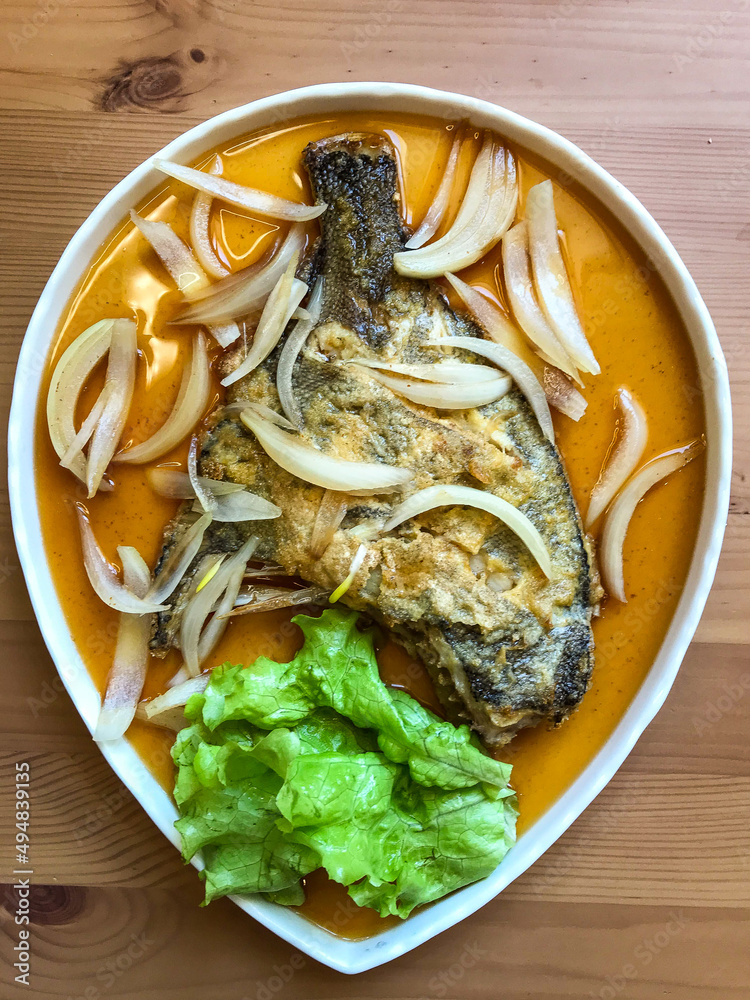 deep-fried flounder with onions and vegetables in Asian sauce on a plate. deep-fried flounder with onions and vegetables in Asian sauce on a plate.