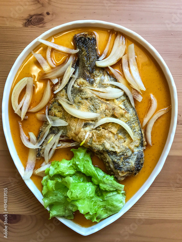 deep-fried flounder with onions and vegetables in Asian sauce on a plate.