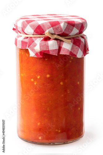 Ajvar in a closed glass jar. Checkered fabric with a string.