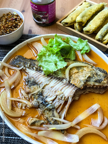 deep-fried flounder with onions and vegetables in Asian sauce on a plate.