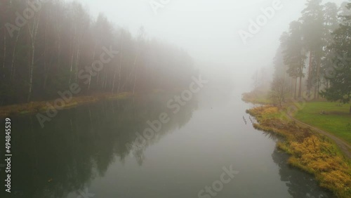 Very thick fog in a coniferous forest with a lake. Top view