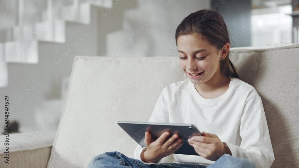 Female teen using tablet for watching cartoons at home Female teen using tablet for watching cartoons at home
