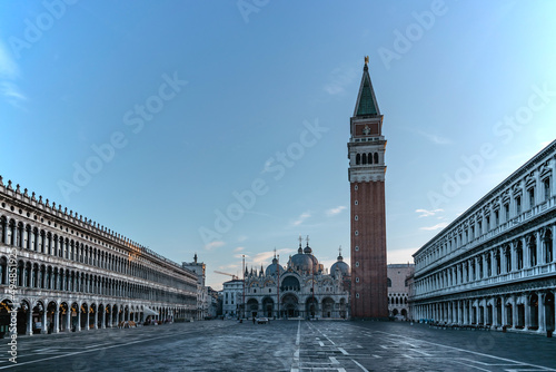 Famous empty San Marco square with Basilica of Saint Mark and Bell Tower at sunrise,Venice,Italy.Early morning at popular tourist destination.World famous Venice landmarks.Postcard view,travel scenery