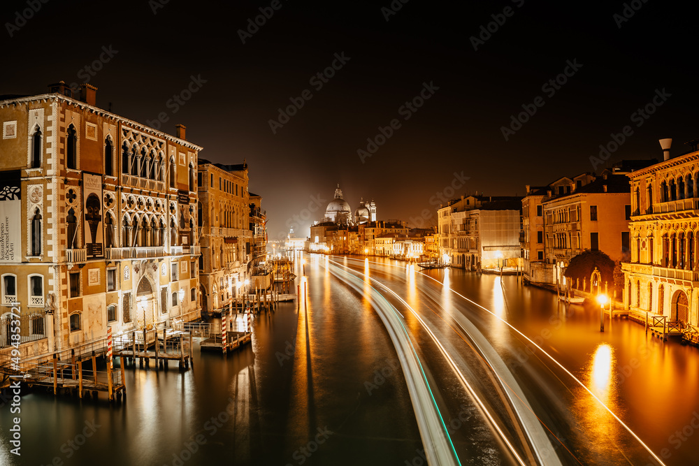 Grand Canal at night,Venice,Italy.Typical boat transportation,Venetian public waterbus long exposure.Water transport.Travel urban scene.Popular tourist destination.Old houses,hotels along canal