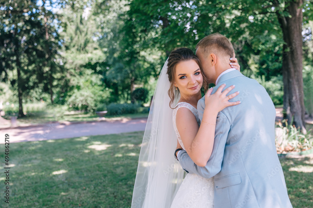 happy bride and groom in the park on their wedding day. A man and a woman are hugging in the park after the ceremony.