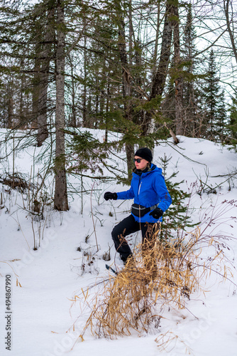 Photography A young woman on snow shoes hiking in the boreal forest