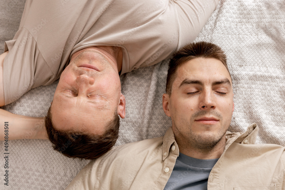 Happy gay couple with casual clothes spending time together at home. Two caucasian men relaxing. Homosexual relationships and alternative love. Cosy interior. Happy gay couple with casual clothes spending time together at home. Two caucasian men relaxing. Homosexual relationships and alternative love. Cosy interior.