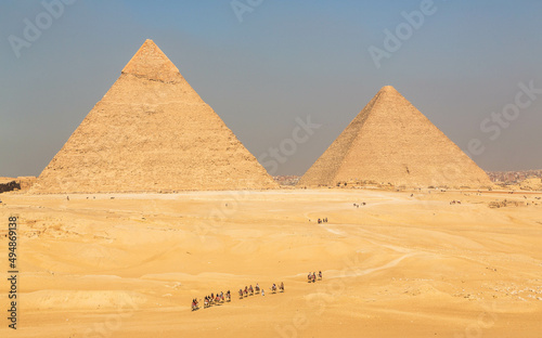 The great Pyramid complex of Giza with tourists riding camels in front of the Egyptian pyramids. Cairo, Egypt