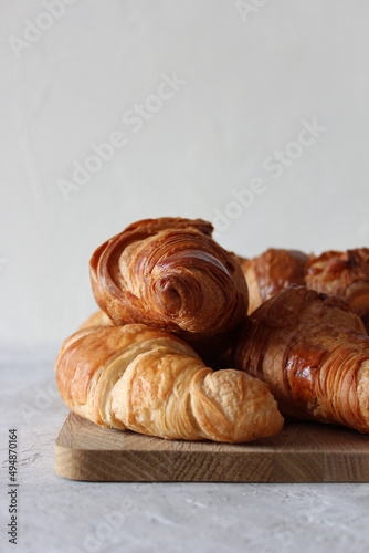 French croissants on the wooden board, on the grey background with copyspace.
