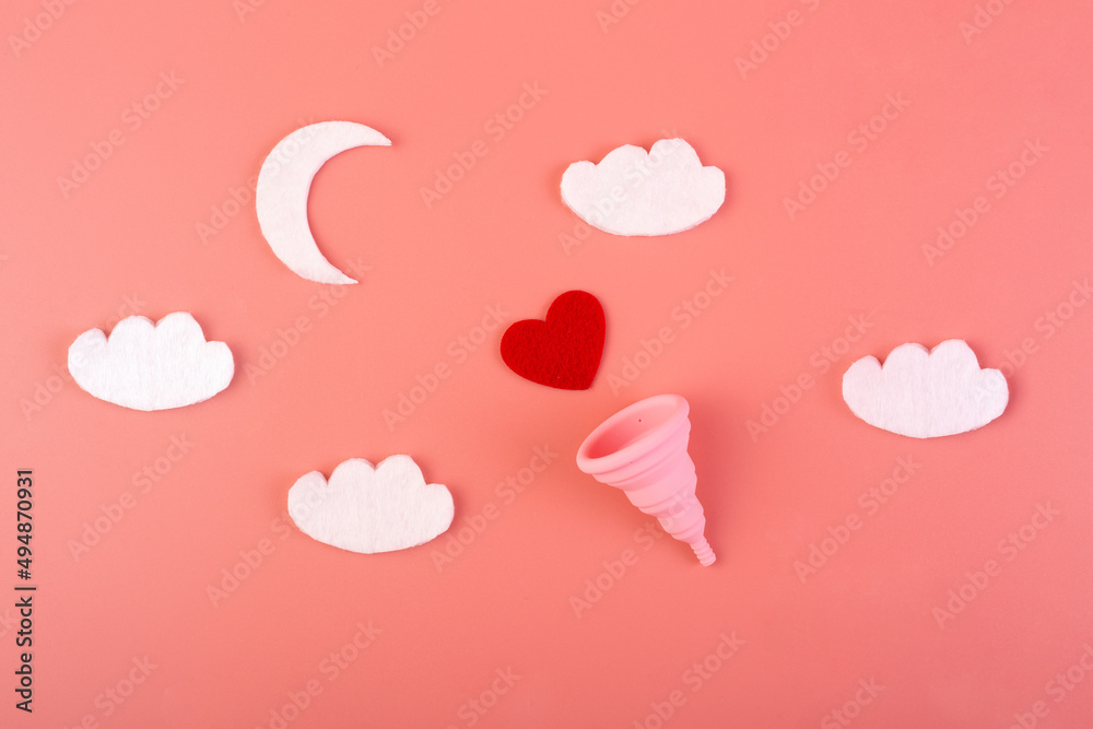 Silicone pink menstrual cup with moon and clouds flatlay on a pink background. Women's health and alternative hygiene. eco-friendly, Alternative reusable product for female hygiene. Concept soft night
