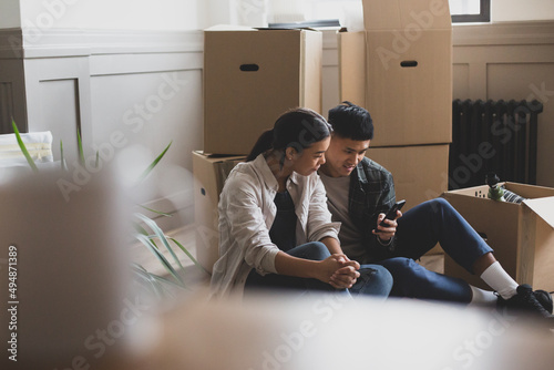 Mid adult couple sitting on the floor of their new home surrounded by boxes