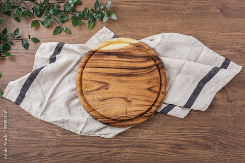 Wooden board, food plate, tray on linen cloth on dark wood table photo