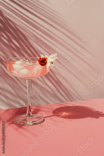 Summer cocktail with pink champagne with ice on the table with shadows from the sun.