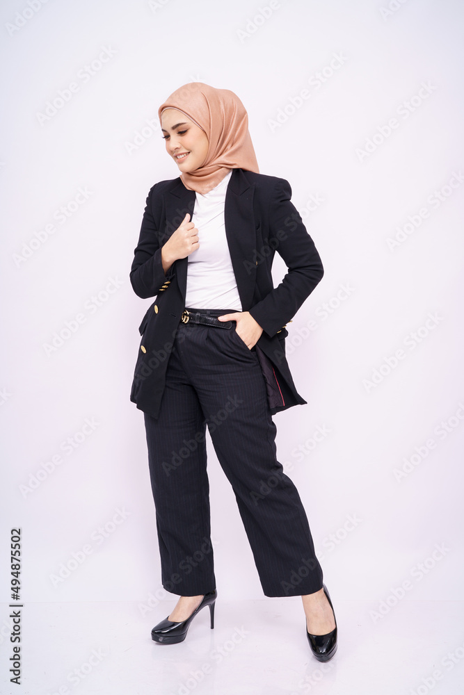 Full length portrait of a beautiful Muslim female model wearing stylish black office attire with hijab isolated over white studio background. Fashion, beauty, corporate, lifestyle concept. Full length portrait of a beautiful Muslim female model wearing stylish black office attire with hijab isolated over white studio background. Fashion, beauty, corporate, lifestyle concept.