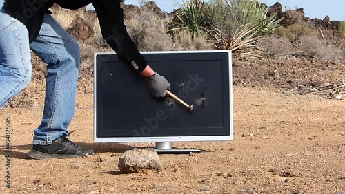 Male young man smashing a tv telvision lcd in the desert