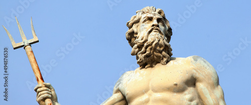 The mighty god of the sea and oceans Neptune (Poseidon) against blue sky background. Fragment of an ancient statue.