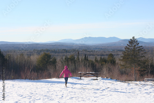 Tableau sur toile Back view of a person in a pink jacket on the snowy Robbins Hill scenic overlook