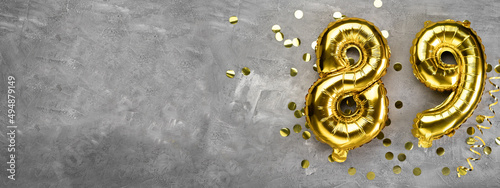 Yellow foil balloon number, number eighty nine on a concrete background. Greeting card with the inscription 89. Anniversary concept. for anniversary, birthday, new year celebration. banner, photo