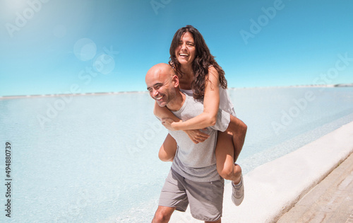Middle-aged Hispanic couple laughing and playing lovingly on the beach