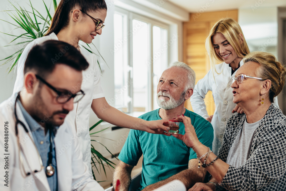 Fototapeta premium Senior Couple In Discussion With Health Visitor At Home. They talk about prescribed therapy and giving urin sample to nurse.