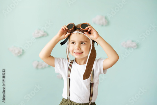 Tableau sur toile A boy in an aviator helmet and suspenders stands on a blue background with clouds and smiles