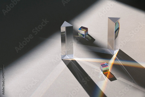dichroic glass cube, prism, with reflection rainbow light beams on neutral background and window light