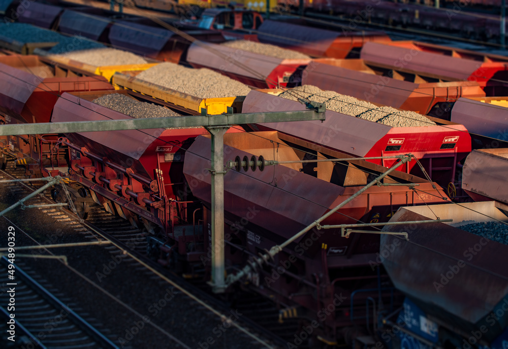 Fototapeta premium Freight station, rails and wagons with stones and gravel bulk cargo in Frankfurt am Main. Transportation and logistics of various goods.