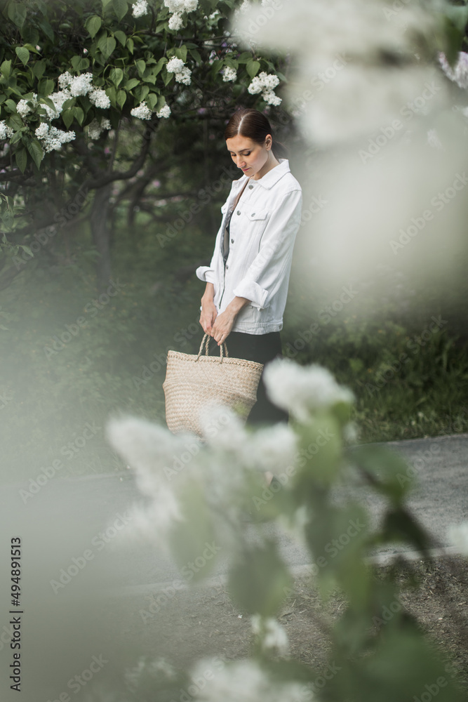 woman holding a basket of white lilacs in her hands