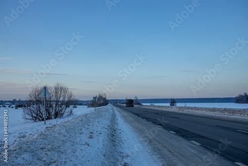 Winter evening landscape, road in the foreground. Sunset sky over the horizon. © Sergei