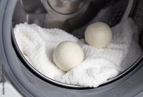 Using wool dryer balls for more soft clothes while tumble drying in washing machine concept. Discharge static electricity and shorten drying time, save energy. photo