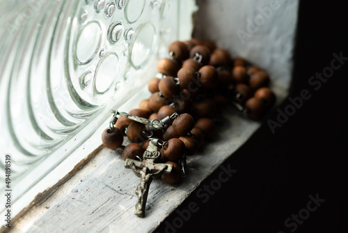 A rosary made of wooden beads placed next to a glass block.