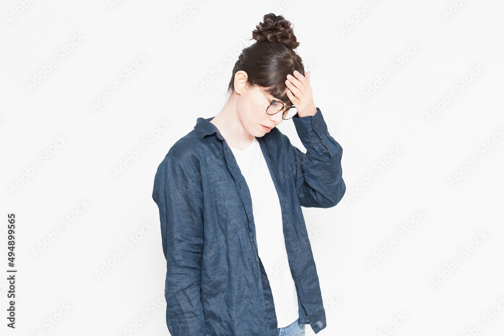 白い背景の前に立っている発熱で額に手を当てる眼鏡をかけている女性 白い背景の前に立っている発熱で額に手を当てる眼鏡をかけている女性