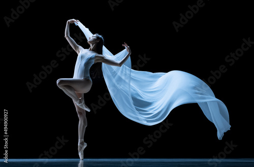 Fototapeta Naklejka Na Ścianę i Meble -  Beauty. Classic ballerina dancing with weightless fabric isolated on black studio background in neon. Theater, art, grace, action and motion concept.