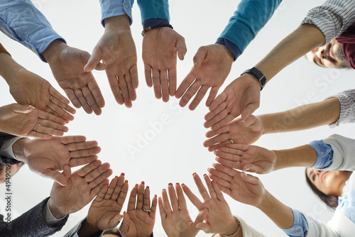 Team of people joining hands. Diverse group of business people standing in circle and putting their hands together. Shot from below, cropped shot, close up. Teamwork, unity, and partnership concepts