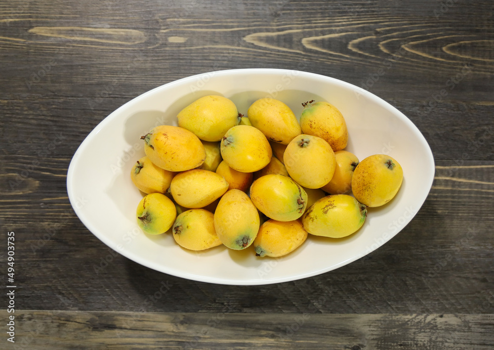 A white bowl with ripe loquats.
