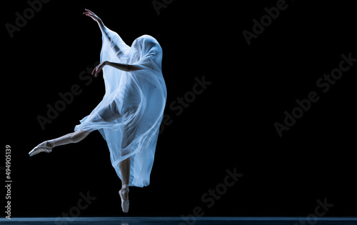 Fototapeta Naklejka Na Ścianę i Meble -  Graceful classic ballerina dancing with weightless fabric isolated on black studio background in neon. Theater, art, beauty, grace, action and motion concept.