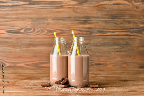 Bottles of delicious chocolate milk on wooden background