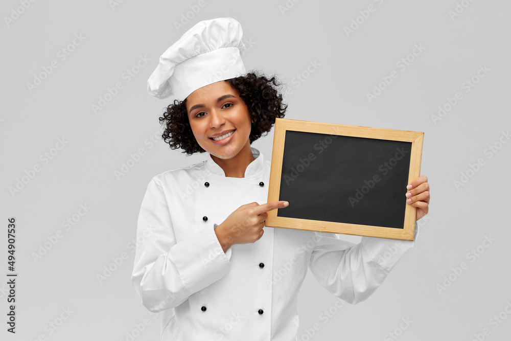 cooking, advertisement and people concept - happy smiling female chef in toque holding black chalkboard over grey background cooking, advertisement and people concept - happy smiling female chef in toque holding black chalkboard over grey background