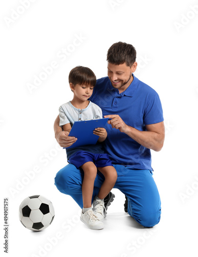 Male trainer with little boy and soccer ball on white background
