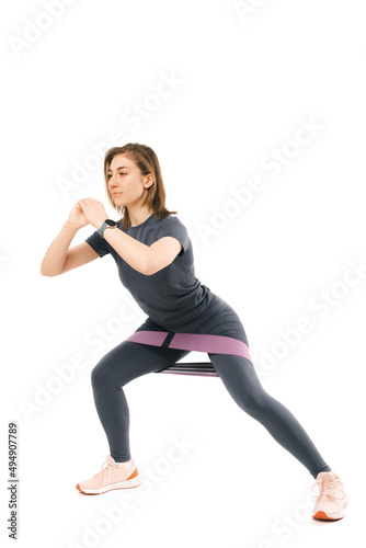 Vertical photo of a young woman performing side squats over white background.