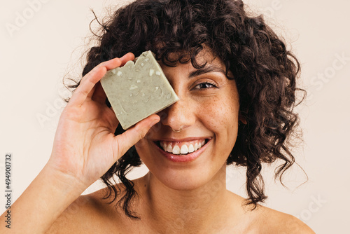 Happy young woman holding a bar of natural soap photo
