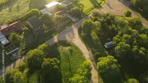 Red tractor cutting grass in park at Fray Bentos in Uruguay. Aerial top-down orbiting photo